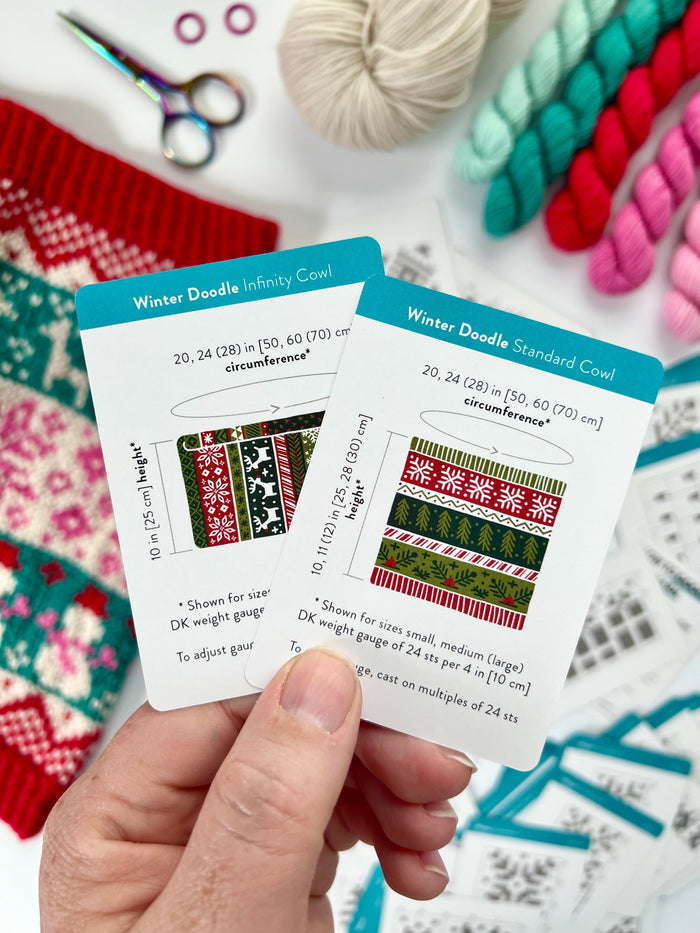 Hand holding the Winter Doodle Infinity Cowl and Standard Cowl schematic cards