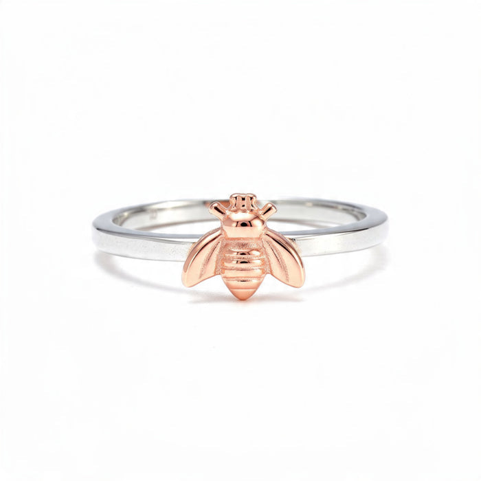 A dainty sterling silver band featuring a detailed rose gold bee charm, centered on a pure white background.