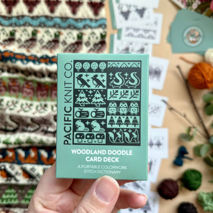 Hand holding the green Woodland Doodle Card Deck by Pacific Knit Co tuckbox