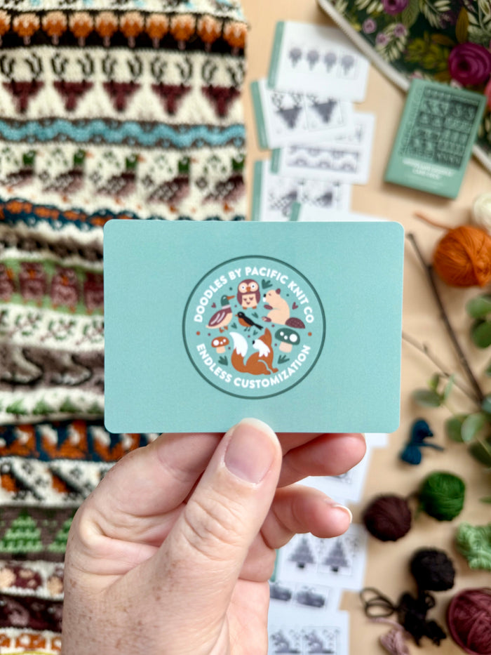 Hand holding the green Pacific Knit Co card back with the Doodles logo