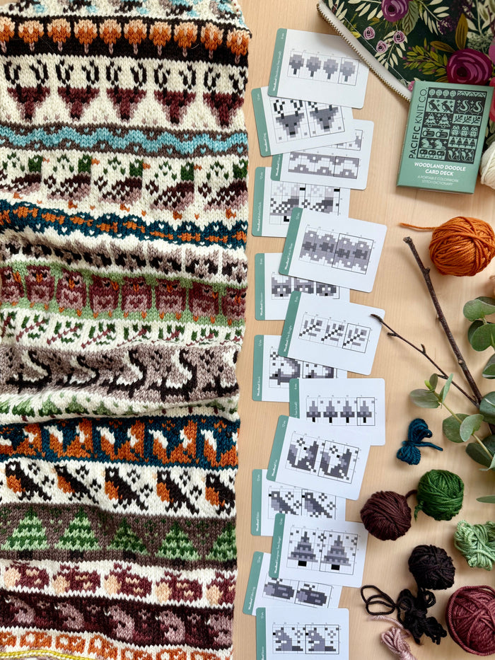Woodland Doodle colorwork knit with fox and deer motifs beside chart cards and the deck
