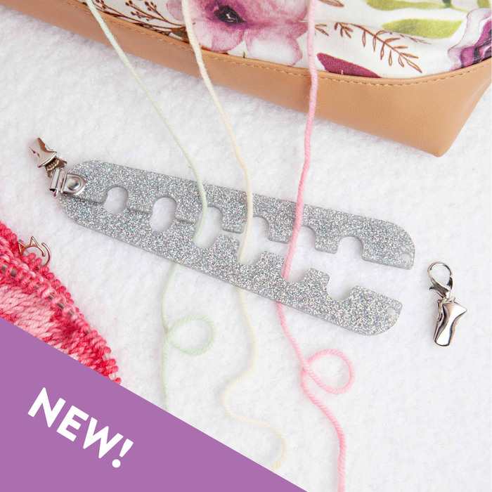 Silver glitter Yarn Gator clipped to a project bag with pink yarn threaded through the slots, showing how it separates colorwork yarns during knitting