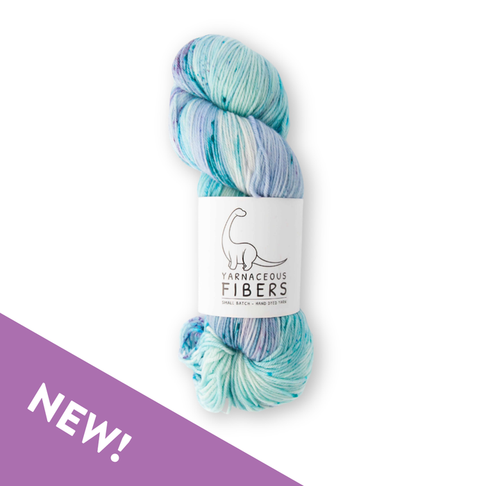 Multicolored skein of yarn with a label on a white background, featuring the brand 'Yarnaceous Fibers'.