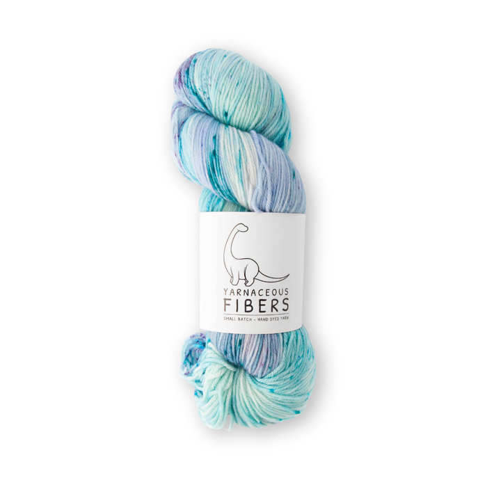 Close-up of Yarnaceous Fibers Daughters of the Deep sock yarn skein showing teal, lavender, and pink hand-dyed speckle detail