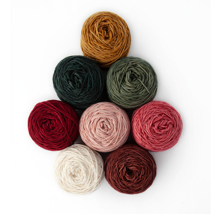 Eight yarn cakes of Yarnaceous Storybook DK Doodle yarn arranged in a diamond formation on a white background viewed from above showing the swirled tops of the center-pull cakes in all eight Storybook colorways