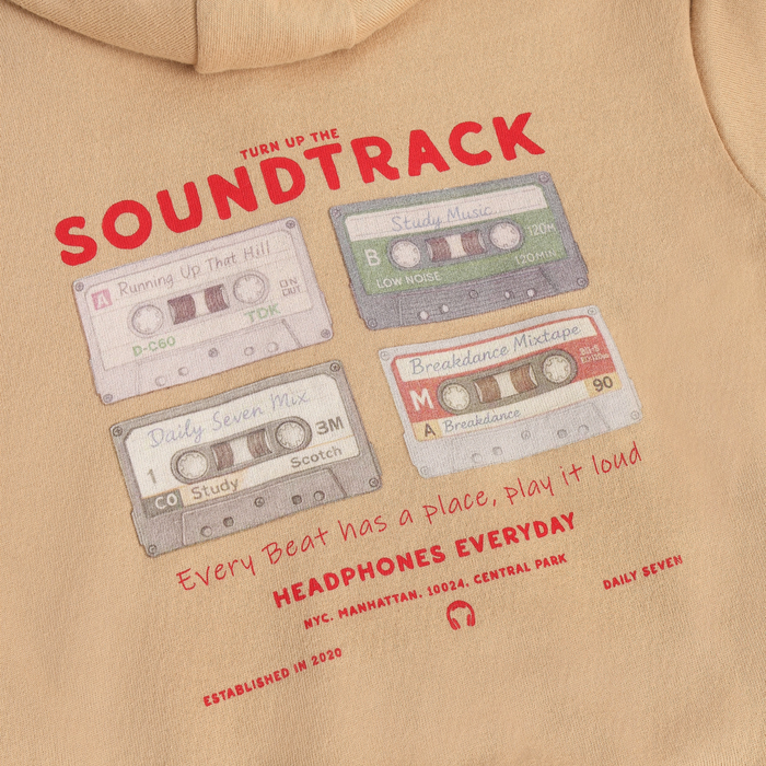 A close up of a beige hoodie shown from the back, featuring a vintage cassette tape graphic with red text that reads 'SOUL' and 'Every Beat has a place, play it loud" HEADPHONES EVERYDAY'.